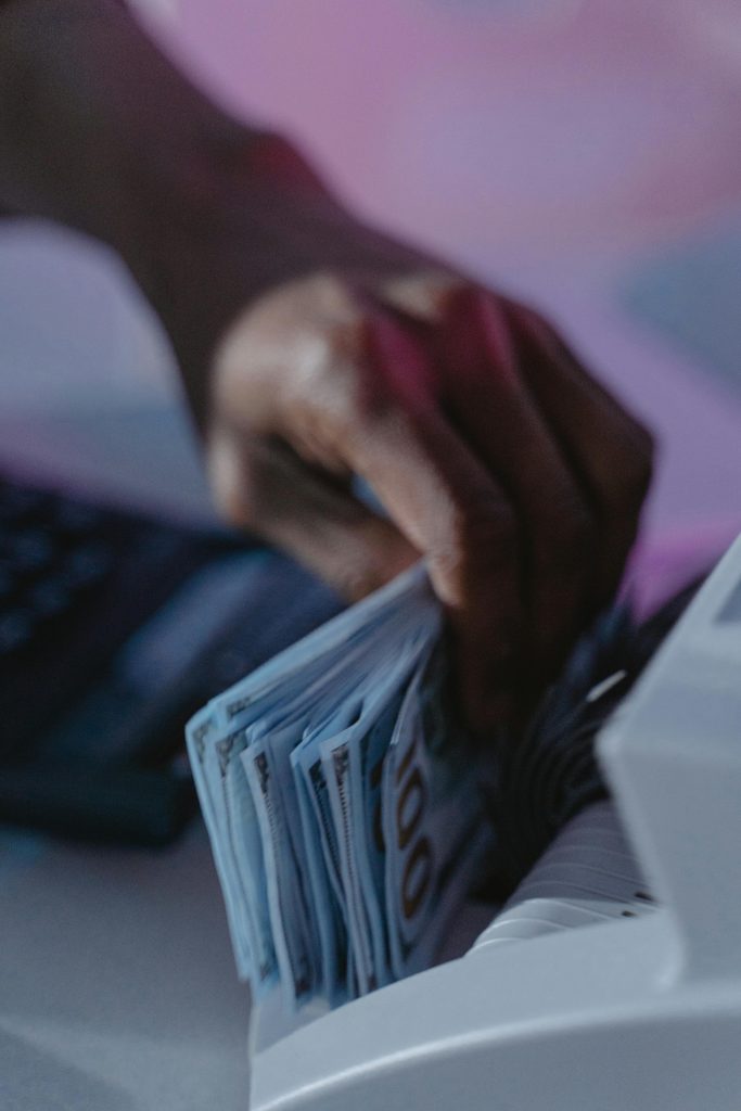 pexels-photo-6266447-6266447 A close-up of a hand using a cash counter machine to sort bills.